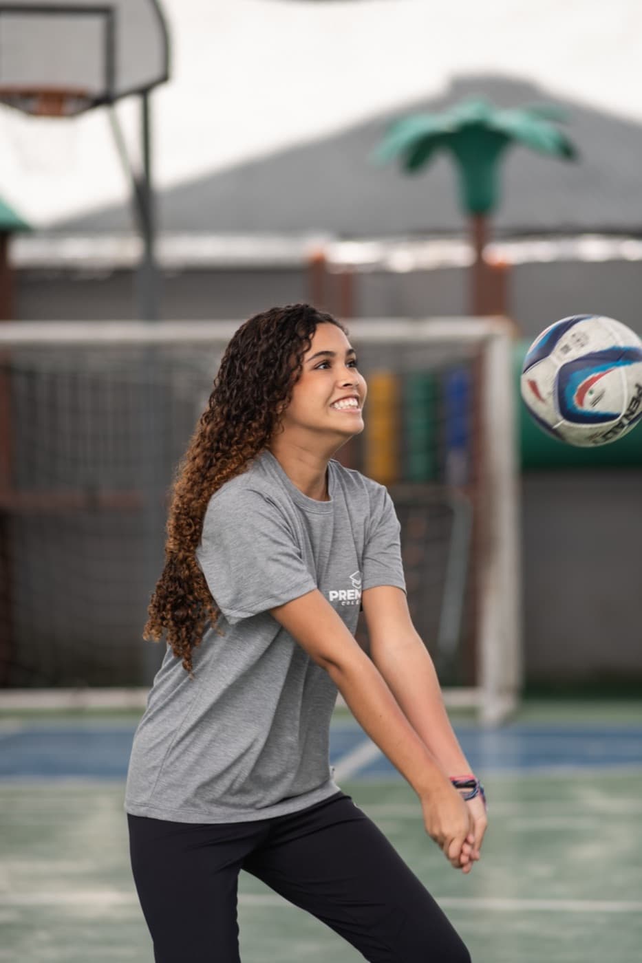 Aluna sorrindo durante recepção de vôlei na quadra do colégio