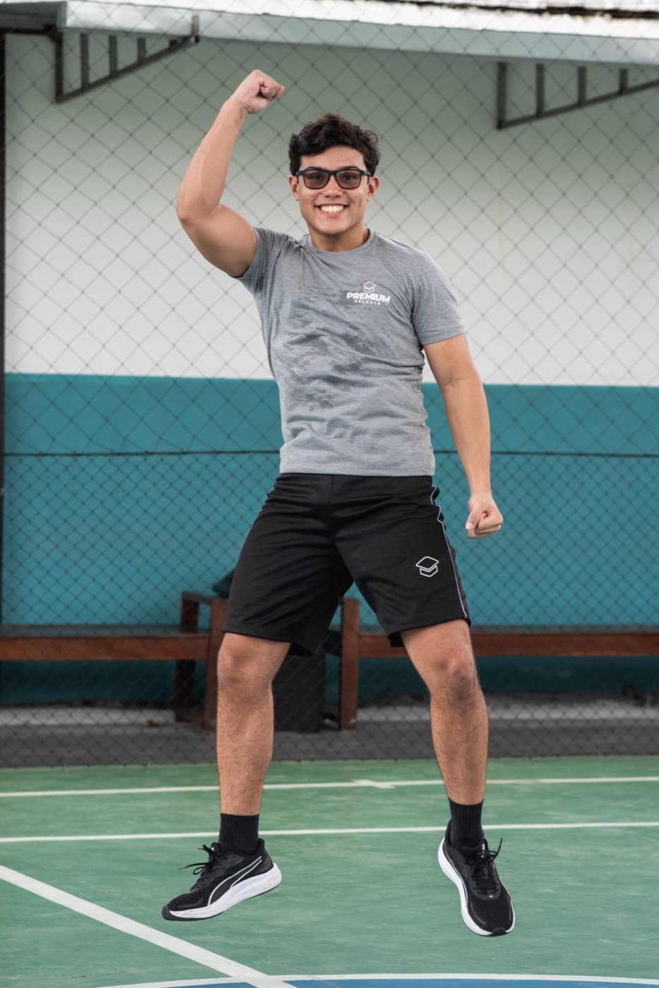 Aluno comemorando com o punho erguido na quadra poliesportiva